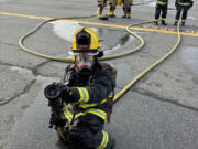 Washougal City Councilor Tia Robertson holds a firehose during the Washington State Council of Firefighters&rsquo; Fire Ops 101 event March 21 in Richland.