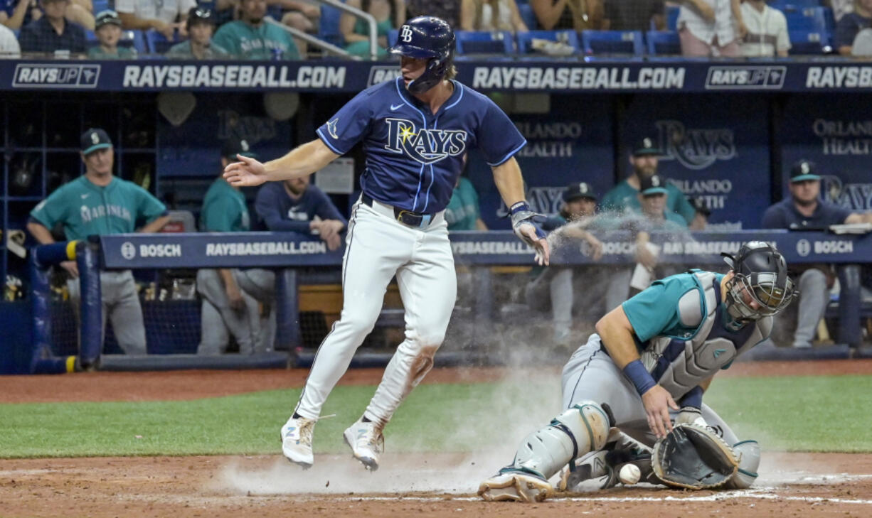 Tampa Bay's Jonny DeLuca scores the go-ahead run as Seattle catcher Cal Raleigh bobbles the throw home.