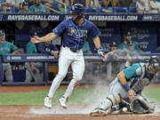 Tampa Bay's Jonny DeLuca scores the go-ahead run as Seattle catcher Cal Raleigh bobbles the throw home.