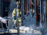 A firefighter stands near the back patio of a burned apartment unit June 11 at the site of a three-alarm fire at the Erica Village apartment complex in Hazel Dell. Regional fire officials are sounding the alarm over a disturbing trend at the start of summer: a rash of destructive fires at multifamily buildings.