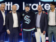 Berkly Catton, center, poses after being selected by the Seattle Kraken during the first round of the NHL hockey draft Friday, June 28, 2024, in Las Vegas.