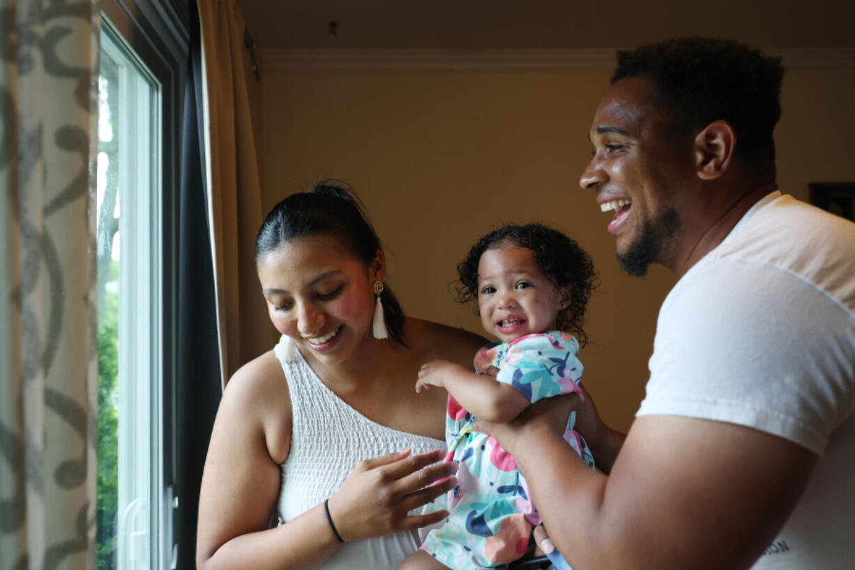 Giselle Rodriguez hands her daughter, Nya, 1, to her husband, Michael Whitley, after picking up Nya and her sister from day care on June 18, 2024, in Bolingbrook. Rodriguez, who emigrated from Mexico without documentation as a child, married Whitley, a U.S. citizen, in 2019, and the couple is expecting their third child next month. (John J.