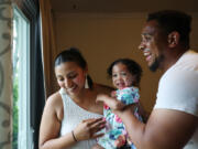 Giselle Rodriguez hands her daughter, Nya, 1, to her husband, Michael Whitley, after picking up Nya and her sister from day care on June 18, 2024, in Bolingbrook. Rodriguez, who emigrated from Mexico without documentation as a child, married Whitley, a U.S. citizen, in 2019, and the couple is expecting their third child next month. (John J.