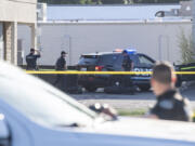 Vancouver police officers stand outside a barricade that hides a body on May 30, 2023, at the site of a fatal police shooting in the Heights Shopping Center parking lot.