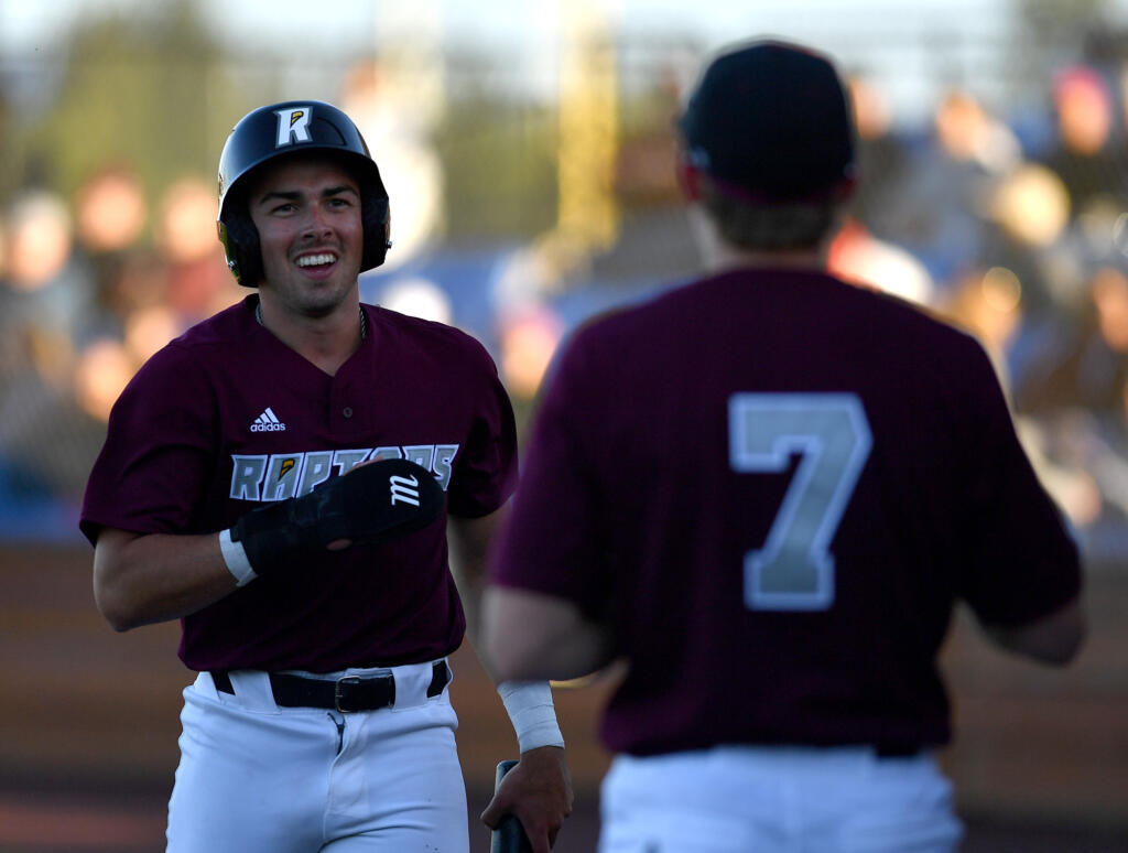 Ridgefield's Kyle Memarian, left, smiles after scoring a run Tuesday June 11, 2024, during the Raptors’ 10-0 win against Yakima Valley Pippins at the Ridgefield Outdoor Recreation Complex.