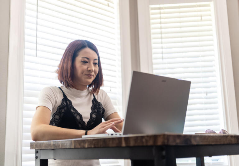 Jasmine Yamamoto turns on her computer to check the eXp Realty site. She purchased her first home in Vancouver last fall.