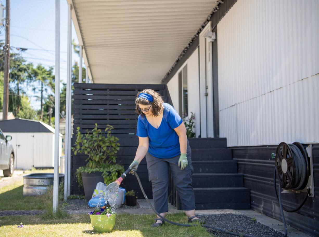 Susan Parrish waters freshly planted flowers at her home in Woodland. Parrish moved into the home last November after a decade of navigating the rental market.