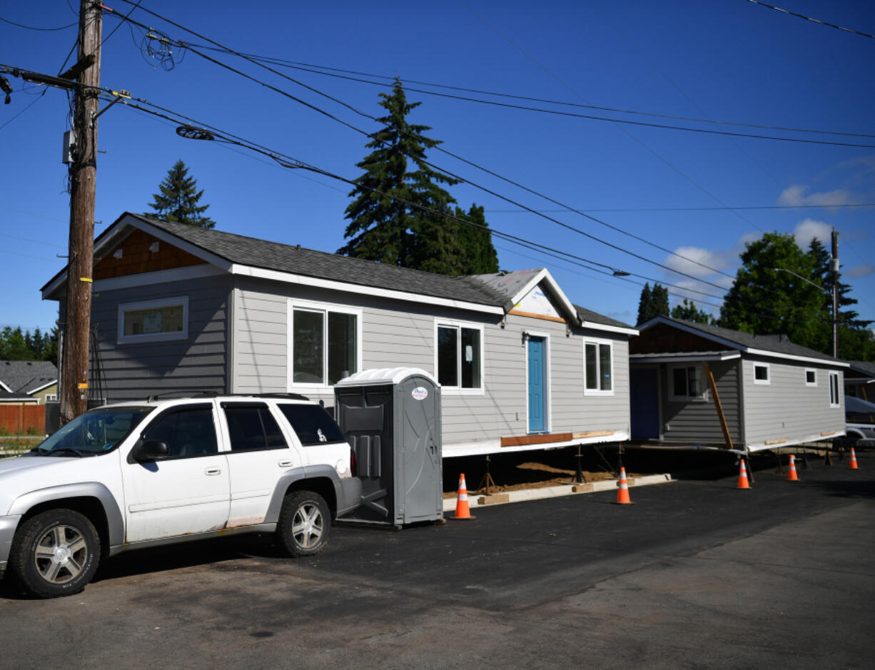 Homes wait to be moved to their final location Friday on O Street in Vancouver. Community Roots Collaborative is creating a pod of seven 730-square-foot tiny homes for people exiting homelessness.