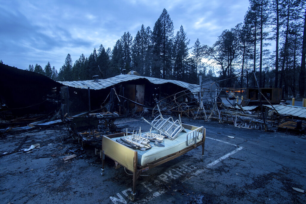 FILE - In this Dec. 4, 2018, file photo, a bed rests outside Cypress Meadows Post-Acute, a nursing home leveled by the Camp Fire, in Paradise, Calif. California state and local officials are encouraging rebuilding in areas destroyed by wildfires at a time when people should be redirected away from those areas if the state wants to reduce the economic and human impact of increasingly destructive wildfires, according to a report published Thursday, June 10, 2021.