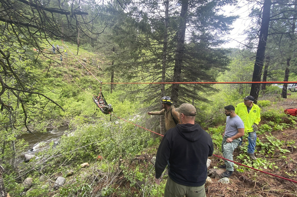 In this image provided by the Baker County Sheriff's Office, responders aid in rescue efforts after a vehicle went into an embankment on U.S. Forest Service Road 39 on June 3, 2024, in Oregon. A dog helped his owner get rescued after the crash by traveling nearly four miles to the campsite where the man was staying with family, which alerted them that something was wrong, authorities said.