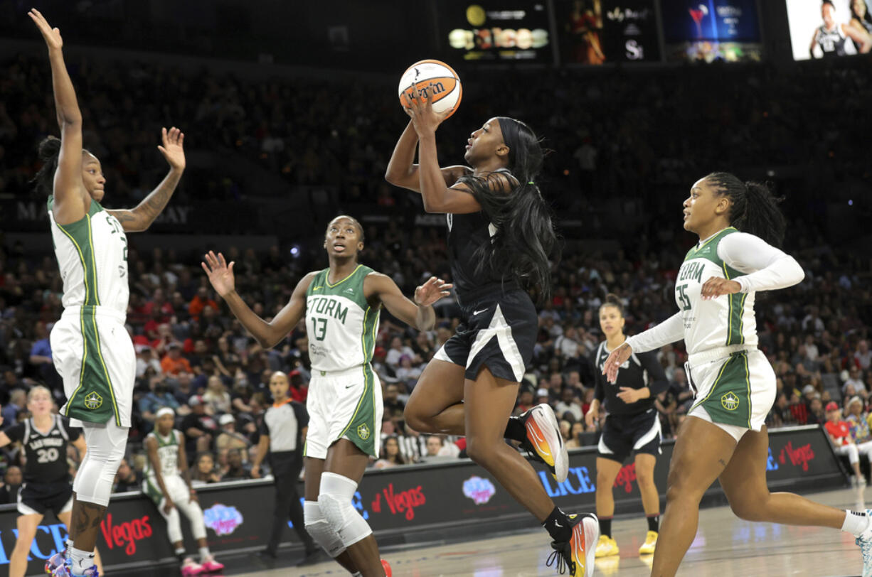 Las Vegas Aces guard Jackie Young (0) shoots a layup against Seattle Storm guard Jewell Loyd, left, center Ezi Magbegor (13) and guard Victoria Vivians (35) during the first half of an WNBA basketball game Wednesday, June 19, 2024, in Las Vegas.