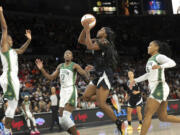 Las Vegas Aces guard Jackie Young (0) shoots a layup against Seattle Storm guard Jewell Loyd, left, center Ezi Magbegor (13) and guard Victoria Vivians (35) during the first half of an WNBA basketball game Wednesday, June 19, 2024, in Las Vegas.