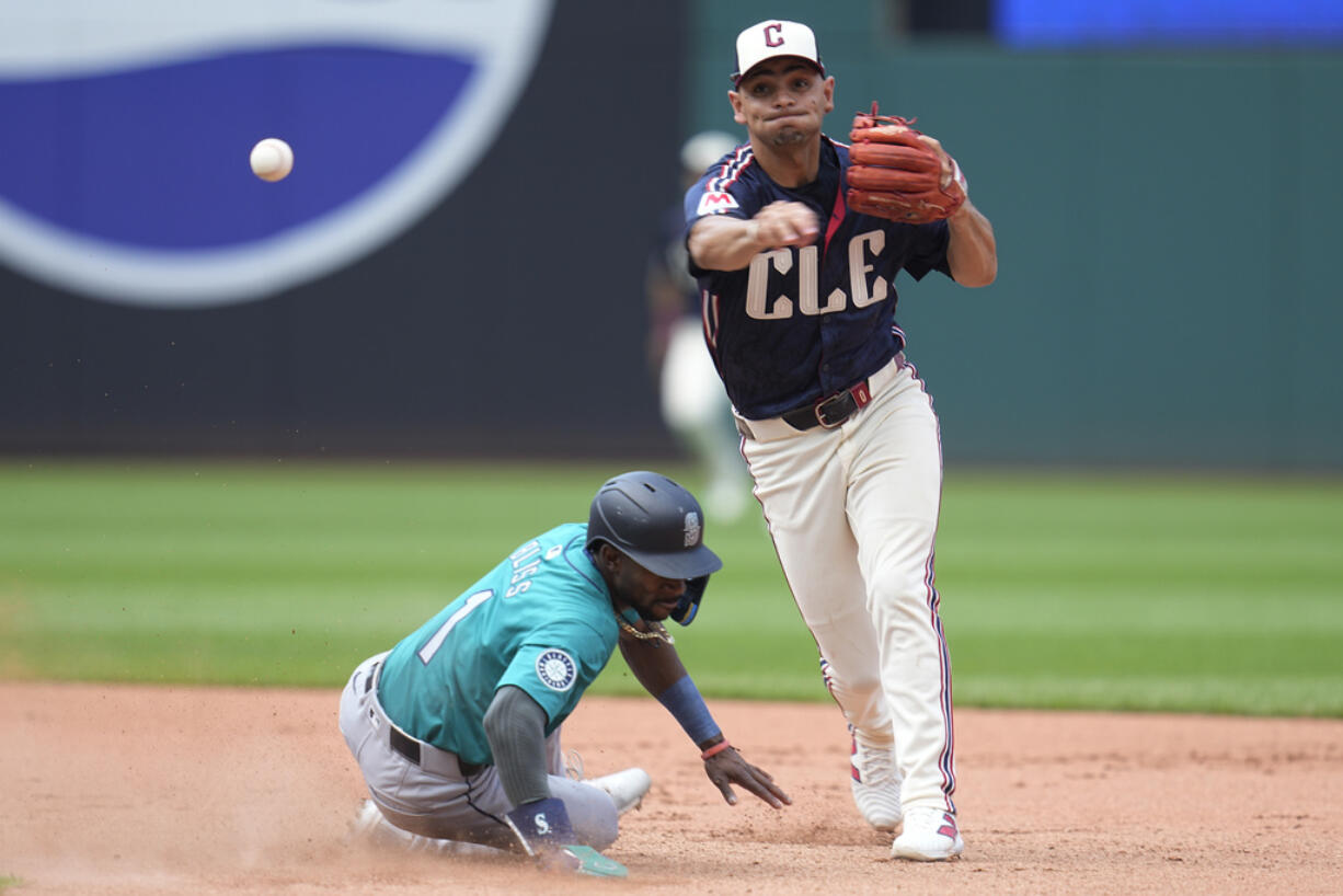 Cleveland Guardians second baseman Andres Gimenez, right, forces out Seattle Mariners' Ryan Bliss, left, out at second base and completes the throw to first base for the out on Dylan Moore in the seventh inning of a baseball game Thursday, June 20, 2024, in Cleveland.