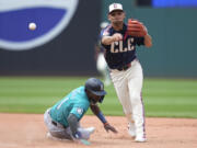Cleveland Guardians second baseman Andres Gimenez, right, forces out Seattle Mariners' Ryan Bliss, left, out at second base and completes the throw to first base for the out on Dylan Moore in the seventh inning of a baseball game Thursday, June 20, 2024, in Cleveland.