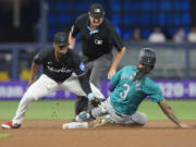 Seattle Mariners' J.P. Crawford (3) steals second base as Miami Marlins second baseman Otto Lopez drops the ball during the first inning of a baseball game against the Miami Marlins, Friday, June 21, 2024, in Miami.