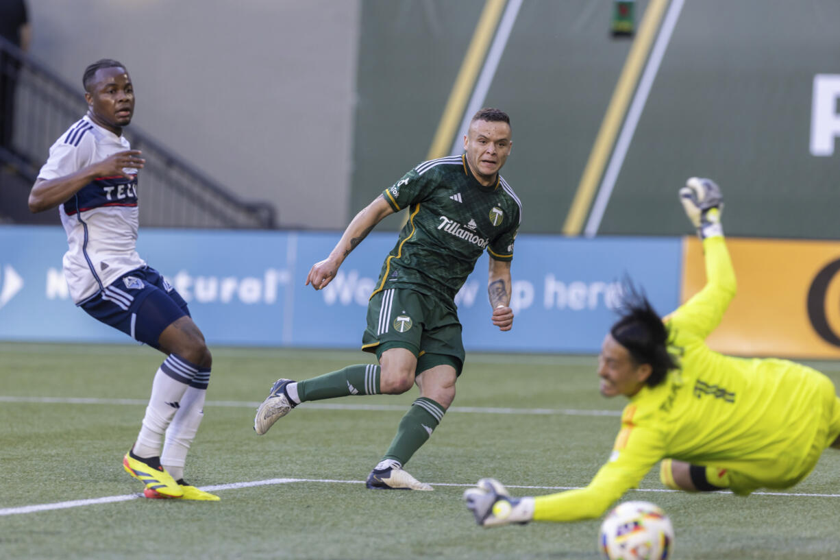 Portland Timbers forward Jonathan Rodríguez, center, scores past Vancouver Whitecaps goalkeeper Yohei Takaoka during the first half of an MLS soccer match Saturday, June 22, 2024, in Portland, Ore.