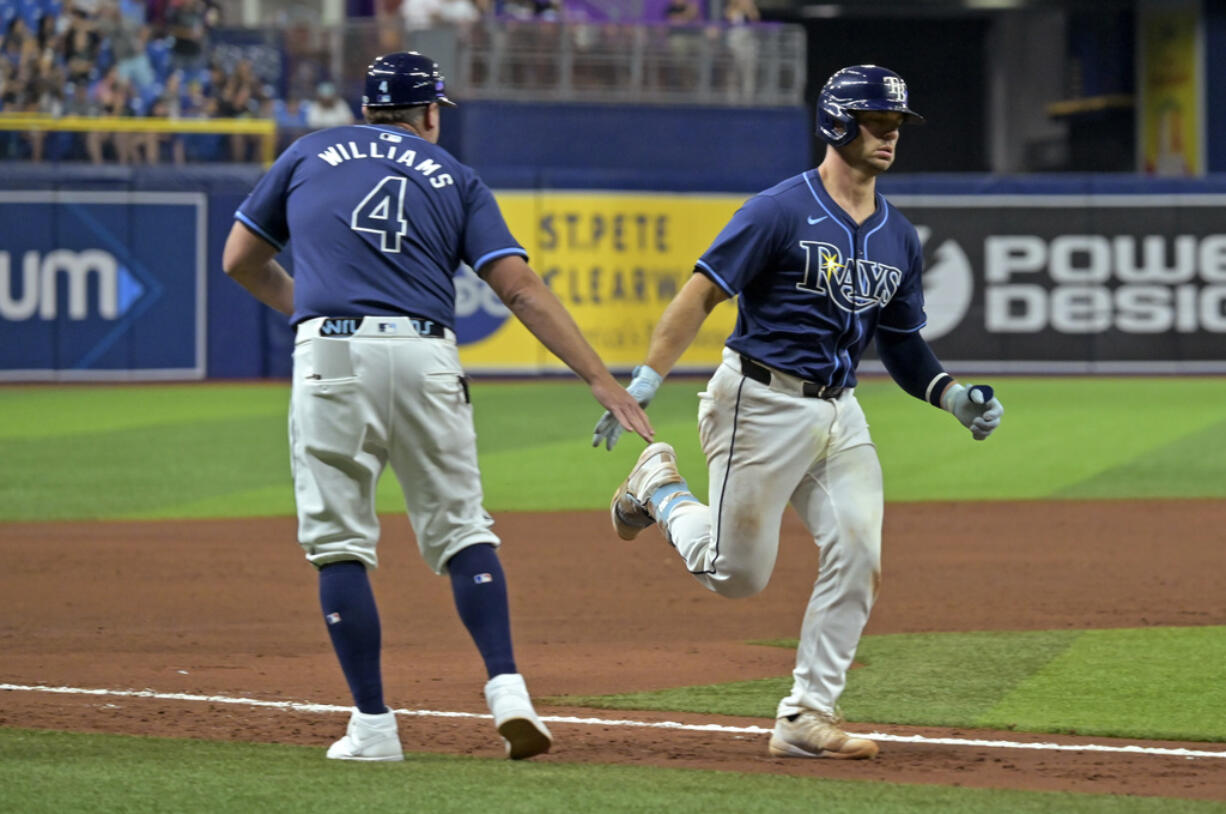 Tampa Bay Rays third base coach Brady Williams (4) congratulates Ben Rortvedt for a two-run home run off Seattle Mariners reliever Mike Baumann during the sixth inning of a baseball game Tuesday, June 25, 2024, in St. Petersburg, Fla.