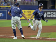 Tampa Bay Rays third base coach Brady Williams (4) congratulates Ben Rortvedt for a two-run home run off Seattle Mariners reliever Mike Baumann during the sixth inning of a baseball game Tuesday, June 25, 2024, in St. Petersburg, Fla.