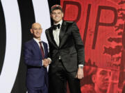 Donovan Clingan, right, poses for a photo with NBA commissioner Adam Silver after being selected by the Portland Trail Blazers as the seventh pick during the first round of the NBA basketball draft, Wednesday, June 26, 2024, in New York.