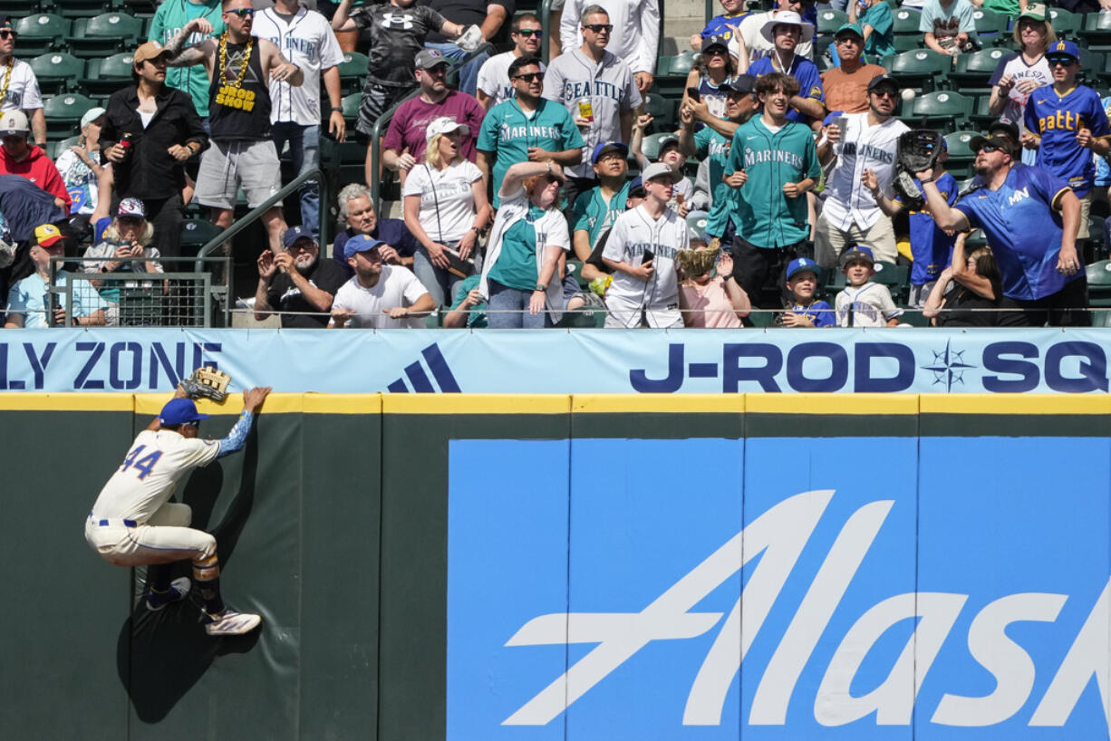 Seattle Mariners center fielder Julio Rodríguez climbs the wall but the two-run home run hit by Minnesota Twins' Trevor Larnach sails into the stands during the eighth inning of a baseball game Sunday, June 30, 2024, in Seattle.