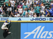 Seattle Mariners center fielder Julio Rodríguez climbs the wall but the two-run home run hit by Minnesota Twins' Trevor Larnach sails into the stands during the eighth inning of a baseball game Sunday, June 30, 2024, in Seattle.