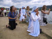 Sister Mary Fatima Pham, second from right, kneels June 23 with her fellow Catholics as they watch the Eucharist brought on board a boat on the Ohio River at the Steubenville Marina in Steubenville, Ohio.