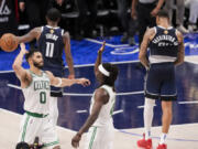 Boston Celtics forward Jayson Tatum (0) and guard Jrue Holiday react as Dallas Mavericks guard Kyrie Irving (11) and forward P.J. Washington walk off away after the Celtics won 109-66 in Game 3 of the NBA basketball finals, Wednesday, June 12, 2024, in Dallas.