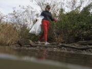 Volunteer Rosemarie Hepner carries a bag during a shoreline trash pickup on Wednesday, Nov. 15, 2023, at Anacostia Park in Washington. For decades, the Anacostia was treated as a municipal dumping ground for industrial waste, storm sewers and trash. A sewer upgrade in the city and decades of local environmental advocacy have brought improvements to the river, but change has come slowly.