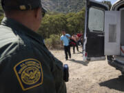 A Border Patrol agent leads a group of migrants seeking asylum towards a van to be transported and processed, Wednesday, June 5, 2024, near Dulzura, Calif. President Joe Biden on Tuesday unveiled plans to enact immediate significant restrictions on migrants seeking asylum at the U.S.-Mexico border as the White House tries to neutralize immigration as a political liability ahead of the November elections.