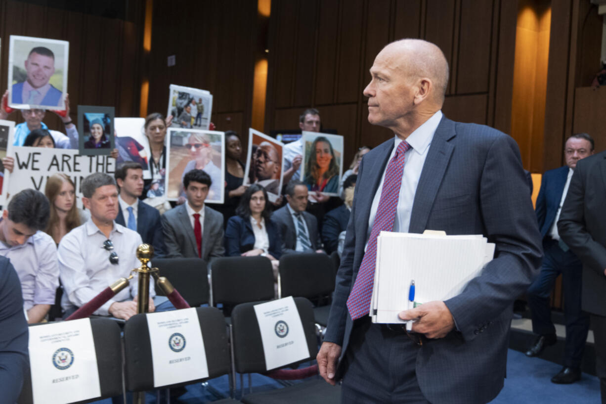 Boeing CEO Dave Calhoun looks at protesters and families of victims as he arrives to testify before the Senate Homeland Security and Governmental Affairs Subcommittee on Investigations to answer to lawmakers about troubles at the aircraft manufacturer since a panel blew out of a Boeing 737 Max during an Alaska Airlines flight in January, at the Capitol in Washington, Tuesday, June 18, 2024.