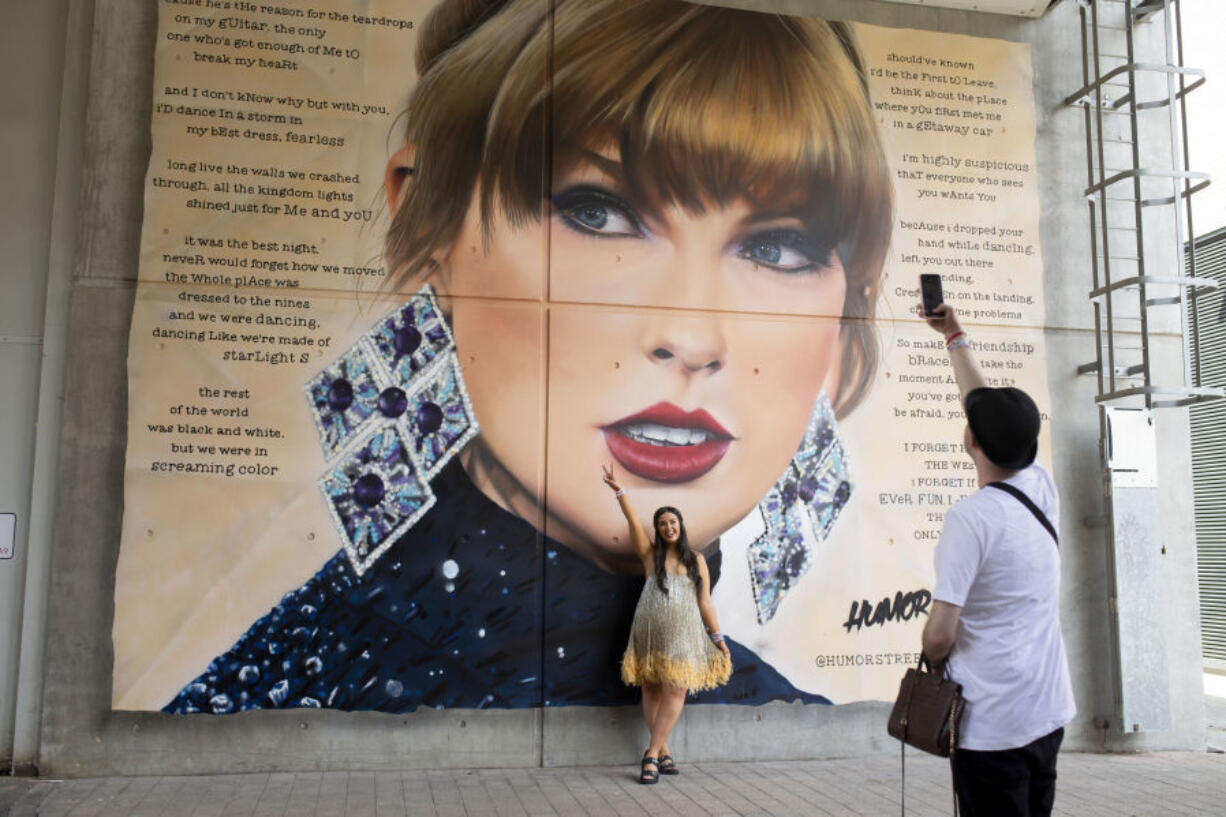 A fan poses in front of a mural of Taylor Swift at Wembley Stadium ahead of her first London concert, during the Eras Tour, in London, Friday June 21, 2024.