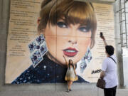 A fan poses in front of a mural of Taylor Swift at Wembley Stadium ahead of her first London concert, during the Eras Tour, in London, Friday June 21, 2024.