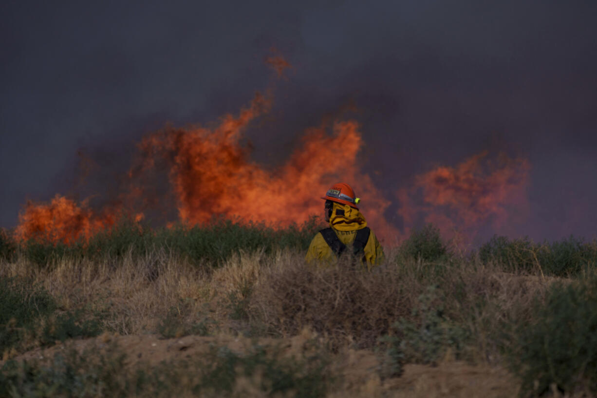 A firefighter looks at flames from the Max Fire on Sunday, June 16, 2024, in Lancaster, Calif.