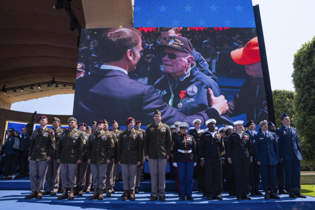 French President Emmanuel Macron is shown handing out a Legion of Honor medal on a screen during a ceremony to mark the 80th anniversary of D-Day, Thursday, June 6, 2024, in Normandy.