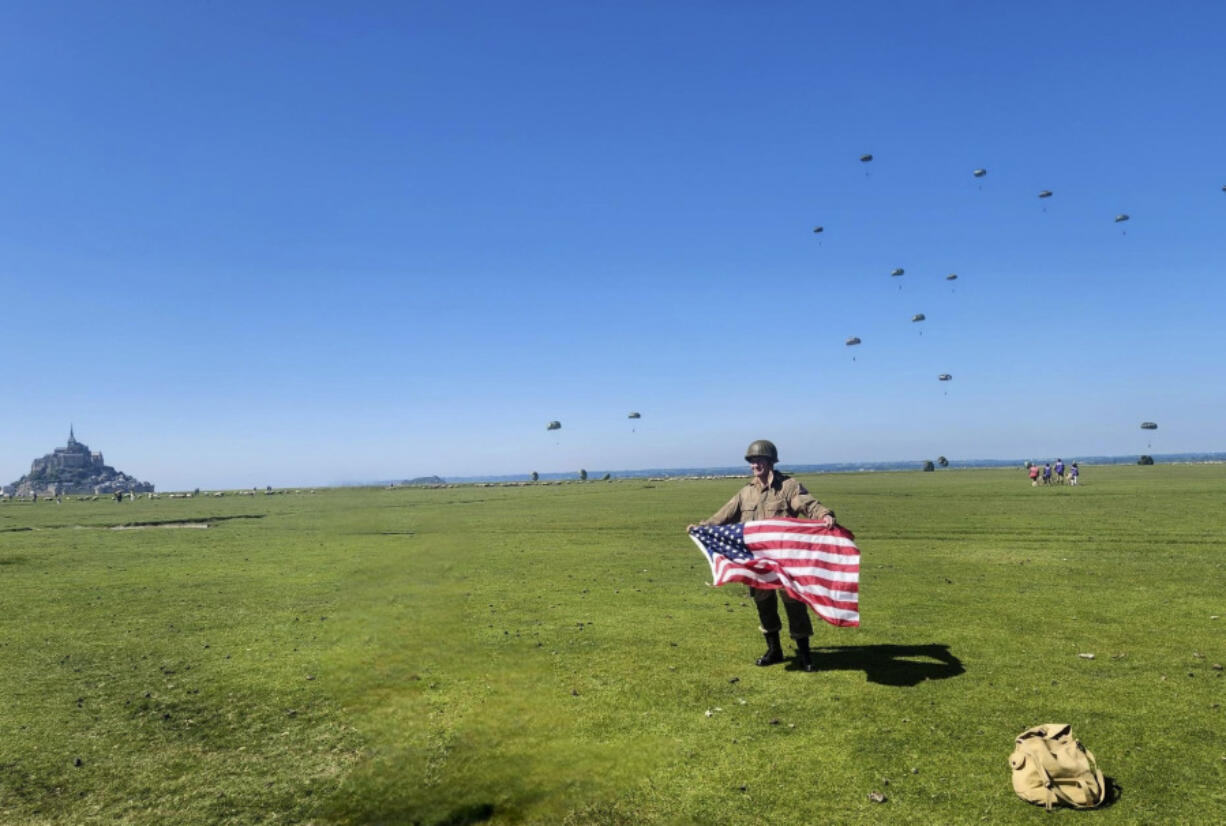 In this provided image, Rep. Mike Waltz, R-Fla., poses with an American flag after participating in a commemorative parachute jump in Normandy, France.