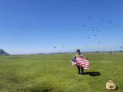 In this provided image, Rep. Mike Waltz, R-Fla., poses with an American flag after participating in a commemorative parachute jump in Normandy, France.