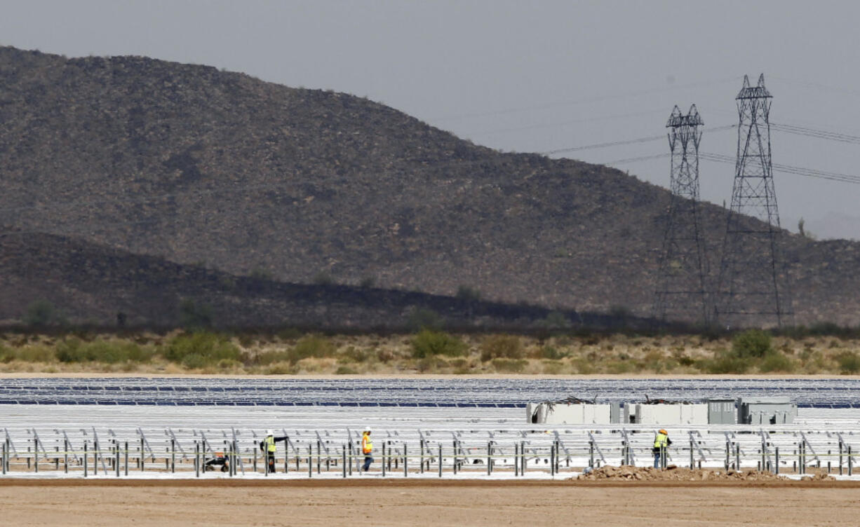 FILE - Workers continue to build rows of solar panels at a Mesquite Solar 1 facility under construction in Arlington, Ariz., Sept. 30, 2011. One of President Joe Biden&rsquo;s signature laws aimed to invigorate renewable energy manufacturing in the U.S. It will also helped a solar panel company reap billions of dollars. Arizona-based First Solar is one of the biggest early winners from the Democrats&rsquo; Inflation Reduction Act, offering a textbook case of how the inside influence game works in Washington.(AP Photo/Ross D.