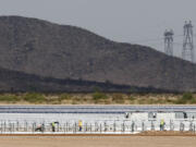 FILE - Workers continue to build rows of solar panels at a Mesquite Solar 1 facility under construction in Arlington, Ariz., Sept. 30, 2011. One of President Joe Biden&rsquo;s signature laws aimed to invigorate renewable energy manufacturing in the U.S. It will also helped a solar panel company reap billions of dollars. Arizona-based First Solar is one of the biggest early winners from the Democrats&rsquo; Inflation Reduction Act, offering a textbook case of how the inside influence game works in Washington.(AP Photo/Ross D.