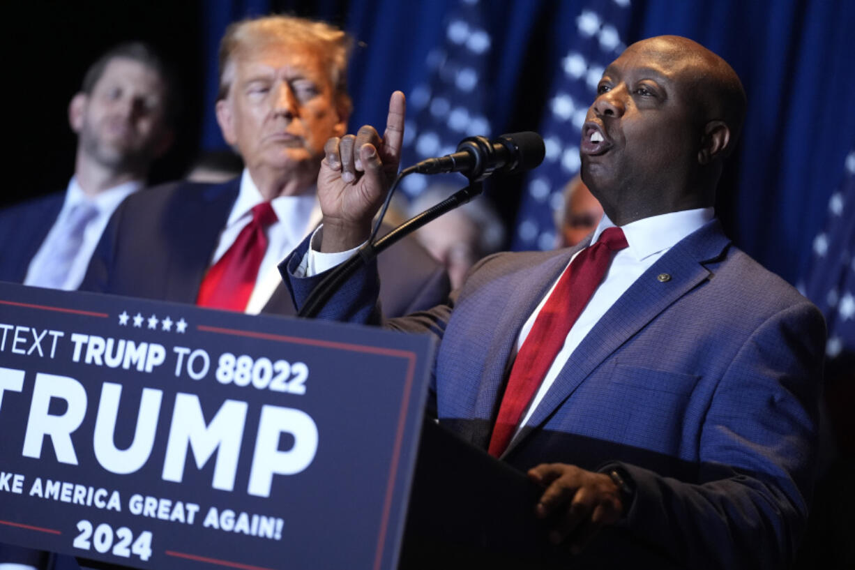 FILE - Republican presidential candidate former President Donald Trump listens as Sen. Tim Scott, R-S.C., speaks at a primary election night party at the South Carolina State Fairgrounds in Columbia, S.C., Saturday, Feb. 24, 2024. A top ally of former President Donald Trump &mdash; and a potential running mate &mdash; is launching a new effort to win over Black and other nonwhite working class voters he argues could be the deciding factor in November&rsquo;s elections. South Carolina Sen. Tim Scott, the only Black Republican in the Senate, will lead a $14 million campaign targeting minority voters in seven key swing states.