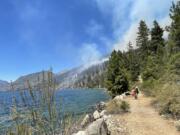 Firefighters are using the Lakeshore Trail along Lake Chelan to access parts of the Pioneer Fire. Smoke from the fire is visible in the background.