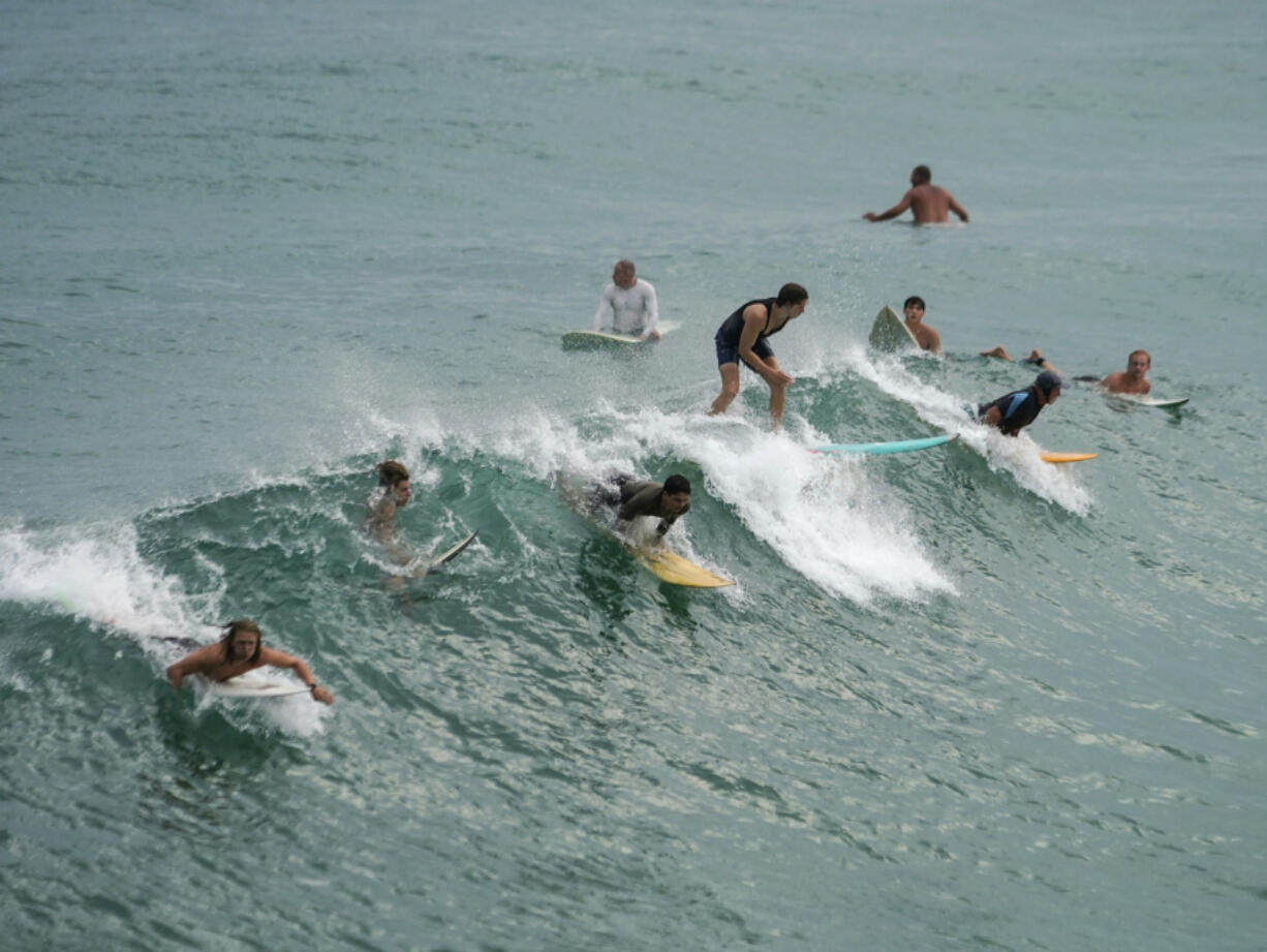 Surfers catch a wave in Navarre Beach, Fla., Sunday, June 16, 2024.