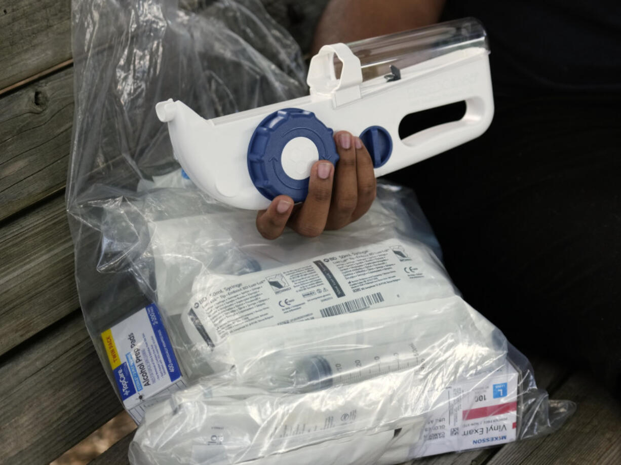 Camden Alderman, 21, who has a rare disease called Wiskott-Aldrich syndrome, holds some of the drugs and medical equipment he uses near his home in Greensboro, N.C., Wednesday, June 12, 2024.