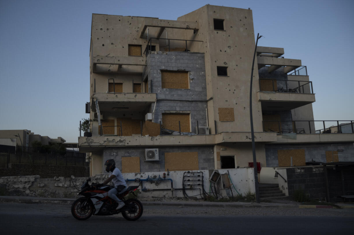 A man drives his motorcycle past a damaged building, from previous shelling attacks from Lebanon, in Kiryat Shmona, northern Israel, Wednesday, June 19, 2024. Hezbollah began attacking Israel almost immediately after the Israel-Hamas war erupted on Oct. 7. There have been near daily exchanges of fire, though most of the strikes are confined to an area within a few mostly confined to the area around the border.