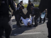 FILE - Israeli police officers remove an ultra-Orthodox Jewish man from the street during a protest against army recruitment in Jerusalem on June 2, 2024. Israel&rsquo;s Supreme Court on Tuesday, June 25, ruled unanimously that the military must begin drafting ultra-Orthodox men for military service, a decision that could lead to the collapse of Prime Minister Benjamin Netanyahu&rsquo;s governing coalition as Israel continues to wage war in Gaza.