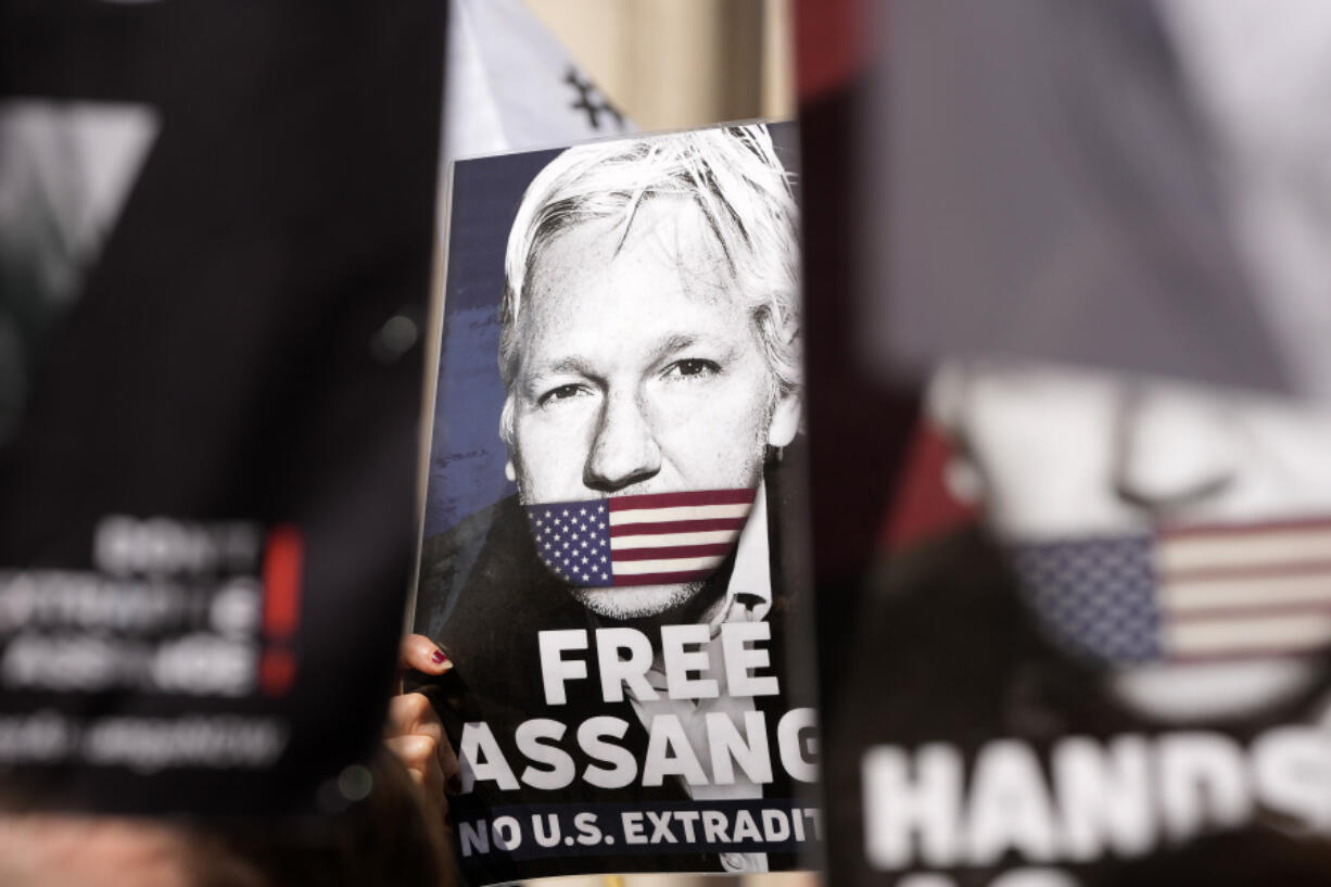 FILE - Protesters hold placards in support of WikiLeaks founder Julian Assange outside the High Court in London, Monday, May 20, 2024. Assange will plead guilty to a felony charge in a deal with the U.S. Justice Department that will free him from prison and resolve a long-running legal saga over the publication of a trove of classified documents.