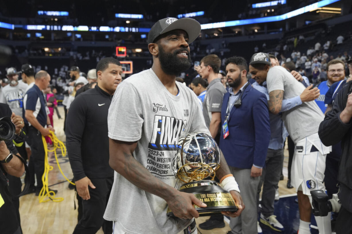 Dallas Mavericks guard Kyrie Irving holds the Western Conference Trophy after Game 5 of the Western Conference finals in the NBA basketball playoffs against the Minnesota Timberwolves, Thursday, May 30, 2024, in Minneapolis. The Mavericks won 124-103, taking the series 4-1 and moving on to the NBA Finals.