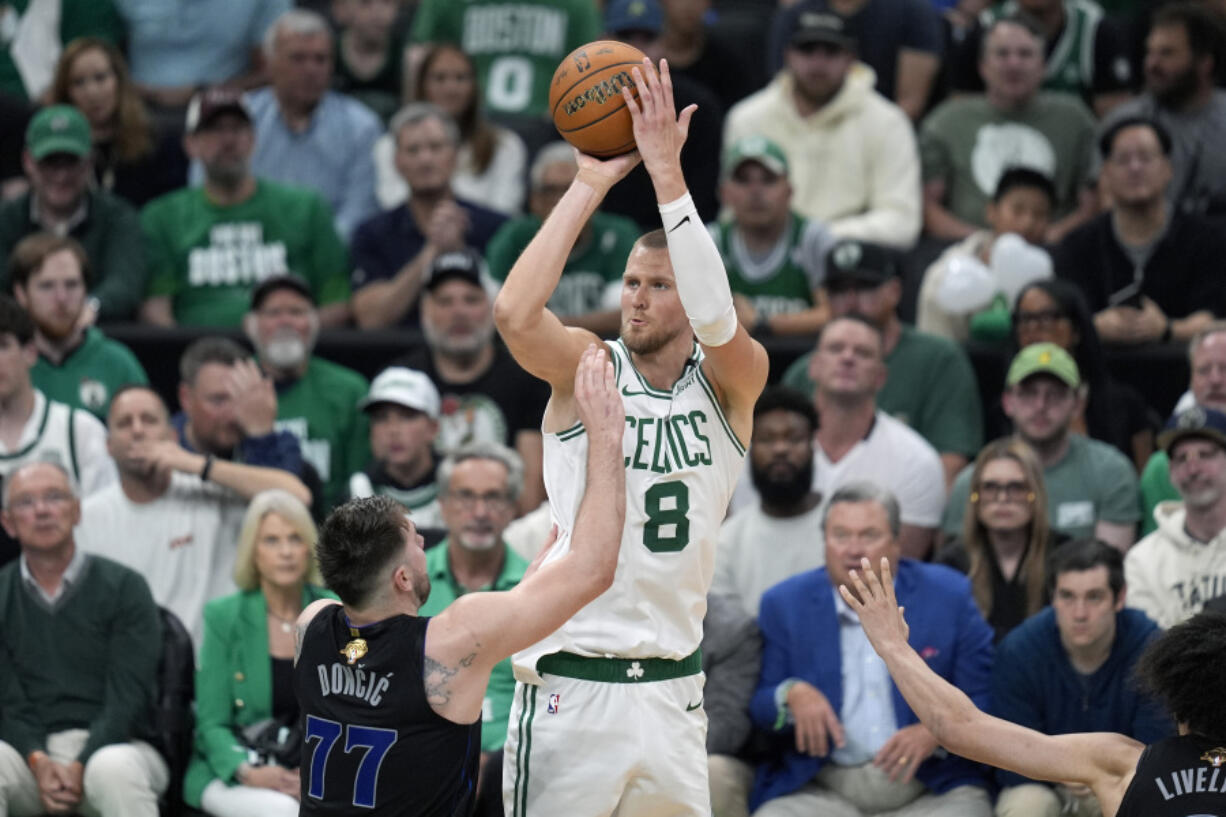 Boston Celtics center Kristaps Porzingis (8) shoots over Dallas Mavericks guard Luka Doncic (77) during the second half of Game 1 of basketball&rsquo;s NBA Finals on Thursday, June 6, 2024, in Boston.