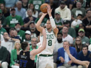 Boston Celtics center Kristaps Porzingis (8) shoots over Dallas Mavericks guard Luka Doncic (77) during the second half of Game 1 of basketball&rsquo;s NBA Finals on Thursday, June 6, 2024, in Boston.