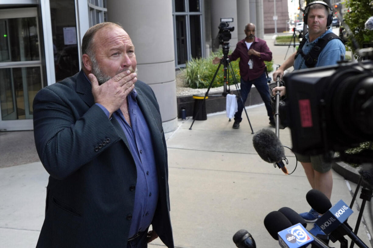 Right-wing conspiracy theorist Alex Jones wipes his mouth as he speaks to the media after arriving at the federal courthouse for a hearing in front of a bankruptcy judge Friday, June 14, 2024, in Houston. The judge is expected to rule on whether to liquidate Jones&rsquo; assets to help pay the $1.5 billion he owes for his false claims that the Sandy Hook Elementary School shooting was a hoax. (AP Photo/David J.