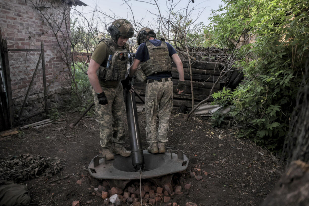 In this photo provided by the 24th Mechanised brigade press service, Ukrainian soldiers prepare to fire 120mm mortar towards Russian position on the front line at undisclosed location in Donetsk region, Ukraine, Monday, June 4, 2024.